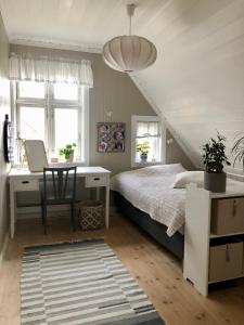 a bedroom with a bed and a desk and windows at Lenes hus in Halden