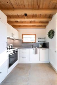 a kitchen with white cabinets and a wooden ceiling at Chalet Buron 7 in Kaufbeuren