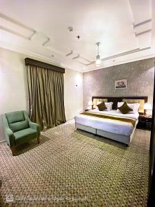 a bedroom with a bed and a green chair at فندق بيوتات المروة biutat almarwa in Jeddah