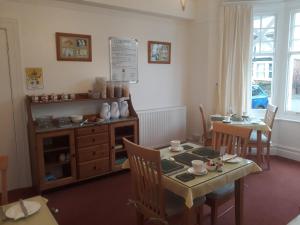 a dining room with a table and a table and chairs at Montrose Guest House in Minehead