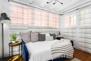 Ce lit se trouve dans un dortoir doté de murs et de fenêtres blancs. dans l'établissement Modern Midtown Getaway - Luxury Chic Unit ✧, à Atlanta