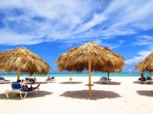 a group of people sitting under straw umbrellas on a beach at Los Corales Beach Village Punta Cana - The original in Punta Cana