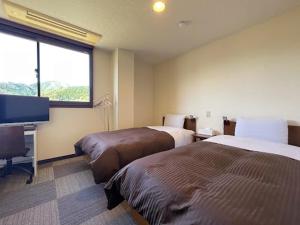a hotel room with two beds and a flat screen tv at 釜石駅から徒歩5分ホテルマルエHotelMarue in Kamaishi