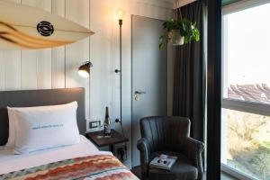 ein Schlafzimmer mit einem Bett, einem Stuhl und einem Fenster in der Unterkunft Beach Motel St. Peter-Ording in Sankt Peter-Ording