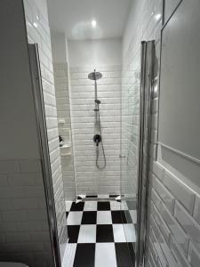 ein Bad mit einer Dusche und einem schwarz-weiß karierten Boden in der Unterkunft Vienna Prater Apartment in Wien