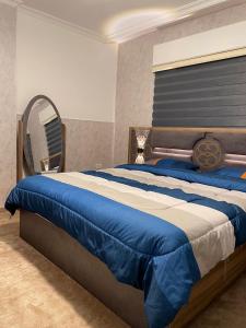 Un dormitorio con una cama azul y blanca con espejo en شركة مسايا لشقق المفروشة, en Irbid