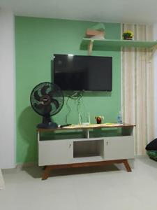 a living room with a tv on a green wall at Cobertura com vista pro mar in Cabo de Santo Agostinho