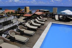 un complejo con piscina, sillas y el océano en Sunbrazil Hotel - Antigo Hotel Terra Brasilis, en Natal