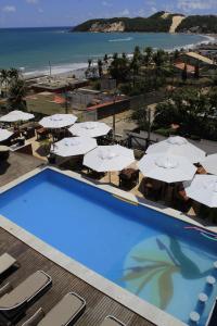 una gran piscina con sombrillas blancas y la playa en Sunbrazil Hotel - Antigo Hotel Terra Brasilis, en Natal
