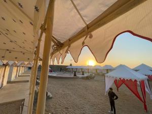 a person walking on a beach under a tent at Golden Empire luxury Resort in Sām