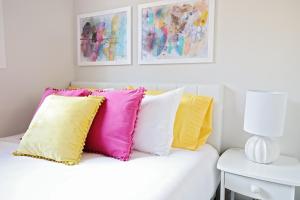 - un canapé blanc avec des oreillers colorés dans l'établissement Downtown 3 Queen Beds,Double Garage,Disney+, à Edmonton