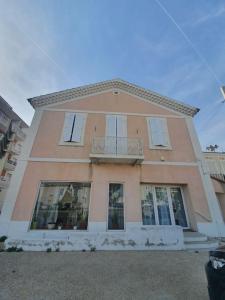 a large pink building with windows and a balcony at La Maison Rose sur le Port in Saint-Louis-du-Rhône