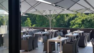 una fila de mesas y sillas bajo un paraguas blanco en Gasthaus zum Dörenberg, en Bad Iburg