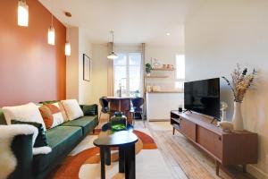 a living room with a green couch and a tv at Luxury Duplex in Boulogne-Billancourt