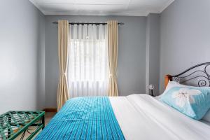 a bedroom with a bed and a window with curtains at Yarkona Hedge in Nairobi