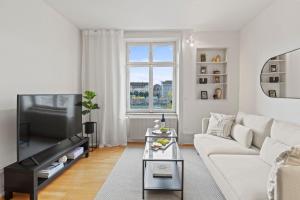 a living room with a white couch and a tv at NEU - Citywohnung mit Rheinblick in Basel