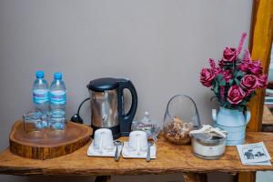 uma mesa com comodidades para preparar café e um vaso de rosas em Tulivu Kilimanjaro Retreat and Campsite em Moshi