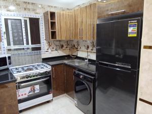 a kitchen with a black refrigerator and a stove at شقة جديدة سوبر لوكس جامعة الدول المهندسين Egyptian Nile Cairo royal furnished apartment in muhandessin in Cairo