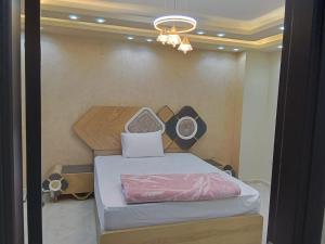 a small bedroom with a bed and a chandelier at شقة جديدة سوبر لوكس جامعة الدول المهندسين Egyptian Nile Cairo royal furnished apartment in muhandessin in Cairo
