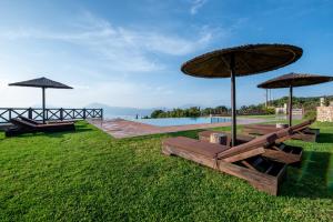 a couple of benches with umbrellas on the grass at Villa Alexandros - Four Seasons in Patra