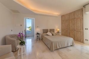 een slaapkamer met een bed, een bank en een tafel bij Hotel Grand Relais Dei Nuraghi in Baja Sardinia
