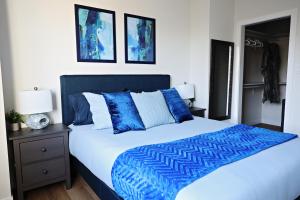 a bedroom with a bed with blue and white sheets at Downtown 3 Queen Beds,Double Garage,Disney+ in Edmonton