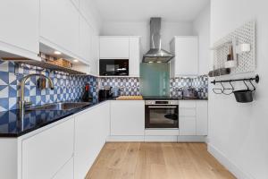 een keuken met witte kasten en blauwe en witte tegels bij Trendy 2 bed Flat in Greenwich with Car Parking in Londen