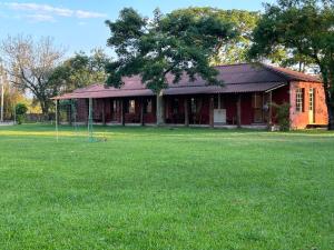 a red house with a large yard in front of it at Pousada Charqueada Costa do Abolengo in Pelotas