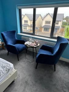 two chairs and a table in a room with a window at 1 luxurious room in family home in Killarney