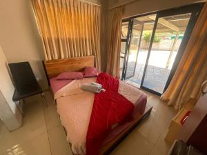 a bedroom with a bed with a red blanket and a window at The Hawks Bed and Breakfast in Harare