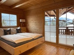ein Schlafzimmer mit einem Bett in einem Zimmer mit Fenstern in der Unterkunft Chalet Kleinbergsonne in Filzmoos