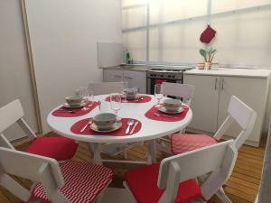 a kitchen with a white table and chairs with plates and wine glasses at Departamento en Centro histórico de Cusco (PASEO LOS HEROES) in Cusco