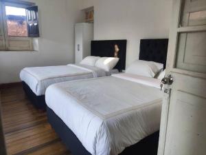 um quarto com três camas com lençóis brancos e uma janela em Departamento en Centro histórico de Cusco (PASEO LOS HEROES) em Cusco