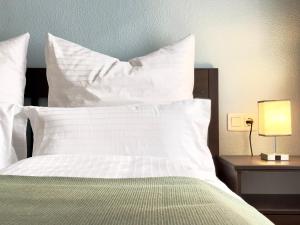 - un lit avec des oreillers blancs et une table avec une lampe dans l'établissement Playa del Cura, 2 Min zum Strand, Zentral, Kostenlos Parken, à Torrevieja