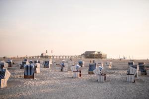 eine Gruppe von Stühlen am Strand mit einem Pier in der Unterkunft Beach Motel St. Peter-Ording in Sankt Peter-Ording