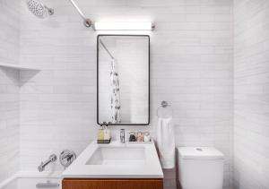 uma casa de banho branca com um lavatório e um espelho em Stunning 2 BED 2 BA At UES em Nova York