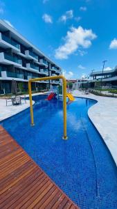 a swimming pool with a slide in front of a building at Makia beach Experience in Porto De Galinhas