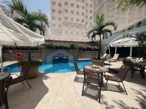 a patio with tables and chairs and a swimming pool at Flat Funchal JK Vila Olímpia Limpeza Diária in São Paulo