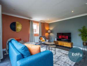 a living room with a blue couch and a tv at Spacious House With Driveway Parking in Southampton