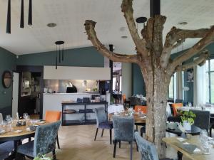 um restaurante com mesas e cadeiras e uma árvore em Hotel Restaurant Le Bosquet em Les Ponts-de-Cé