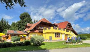 una casa amarilla con techo rojo en Hotel Gasthof Seeblick en Zeutschach