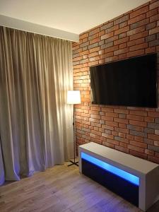 a living room with a television on a brick wall at Apartamenty Bartoszyce 3 in Bartoszyce