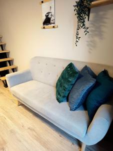 a couch with three pillows on it in a living room at Hola Apartamenty Nawrot in Łódź