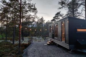 a black tiny house sitting in the woods at Tunnelmallinen ja ihana mökki in Rovaniemi