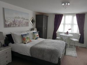 a bedroom with a bed and a table and window at Marjune Guest House in Weymouth