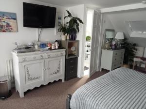 a bedroom with a bed and a dresser with a television on it at Marjune Guest House in Weymouth