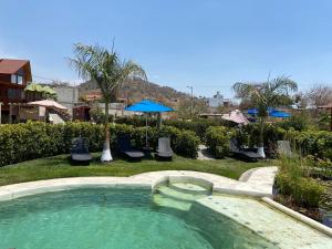 a swimming pool with chairs and an umbrella at Villarreal Lodge Hotel Ecológico in Totolapan