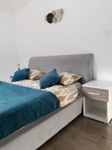 una camera da letto con letto con lenzuola e cuscini blu di Apartman Harmony 2 a Banja Koviljača