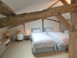 2 letti in una camera con travi in legno di Les ecuries du chateau a Biaudos Altre 17 foto