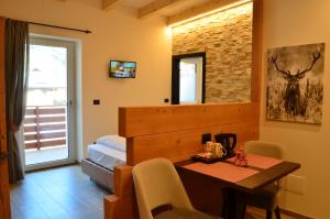 a room with a table and a bed and a window at Aria Alpina Guest House Affittacamere in Predazzo